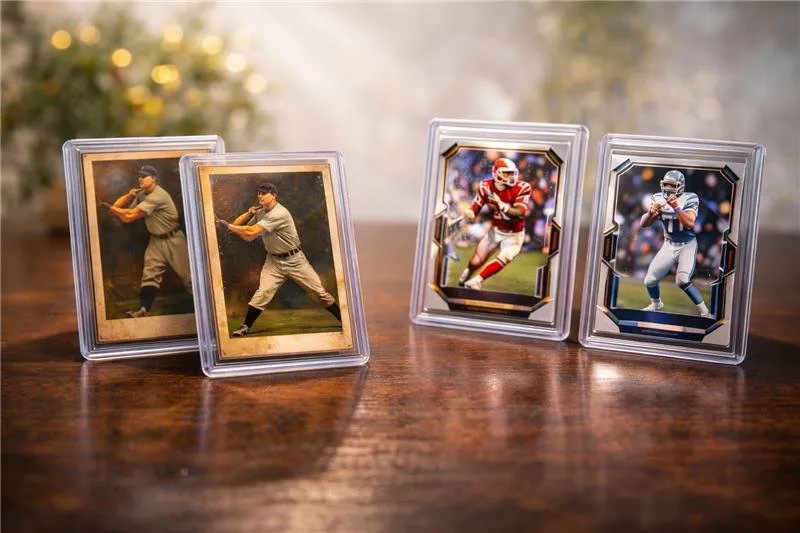 Four collectible sports cards in protective cases on a wooden table